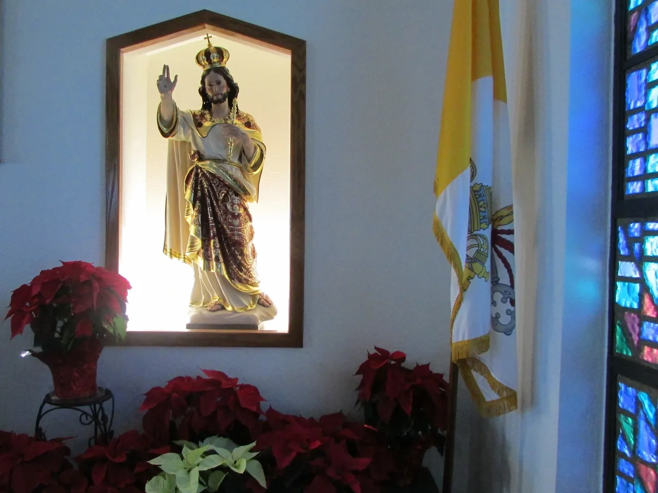 A picture of jesus in the window above some poinsettias.